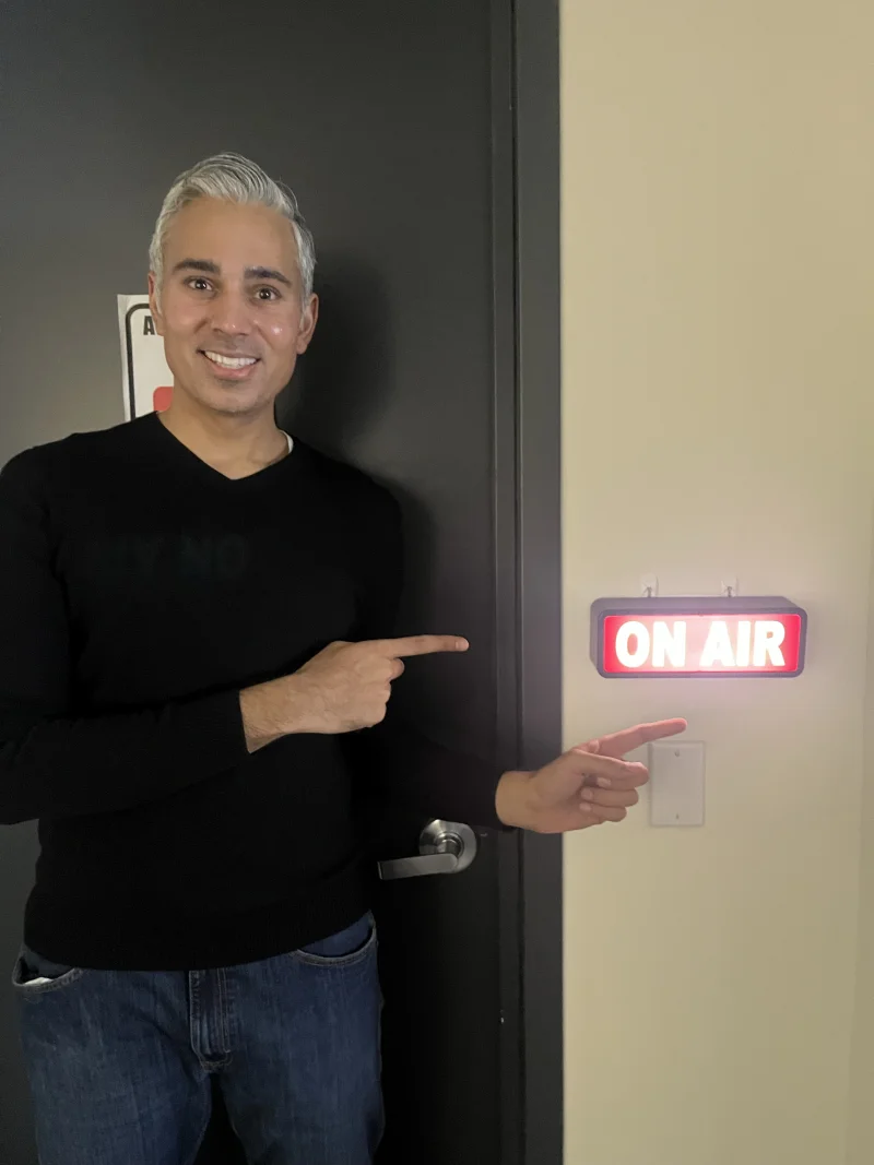 Rupesh Parbhoo pointing at an On Air sign before recording a Speak Arizona podcast episode